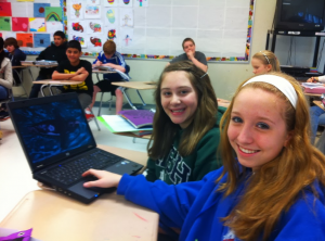 Two students in French class with a laptop.