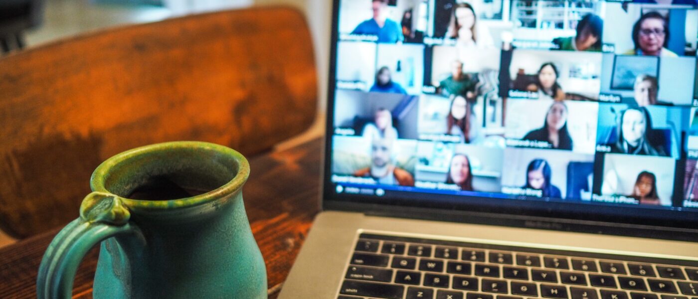 coffee cup next to computer with people in a videoconference