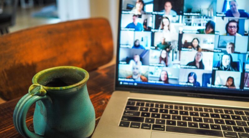 coffee cup next to computer with people in a videoconference