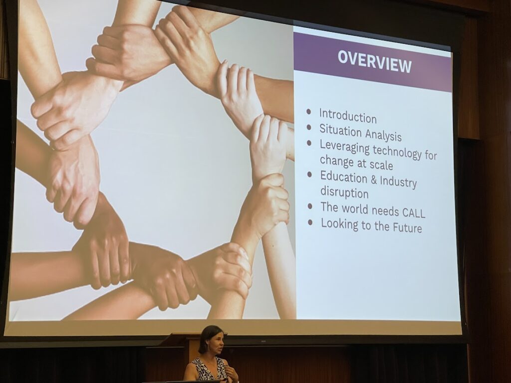 Picture 1 - Dr. Katie Brown delivering her opening keynote. Slide says: Overview: Introduction, Situation Analysis, Leveraging technology for change at scale, Education and industry disruption, The world needs CALL, Looking to the future