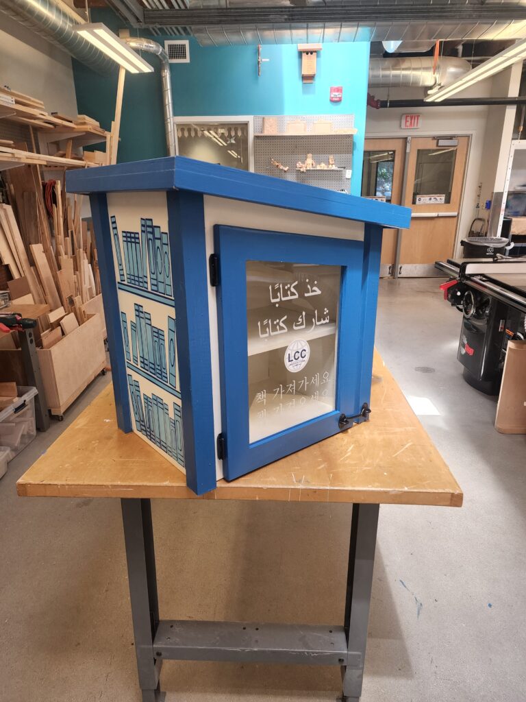 Picture 5 - The side of a finished box (Getting close!) - a little free library with Arabic on the front and pictures of books on the side